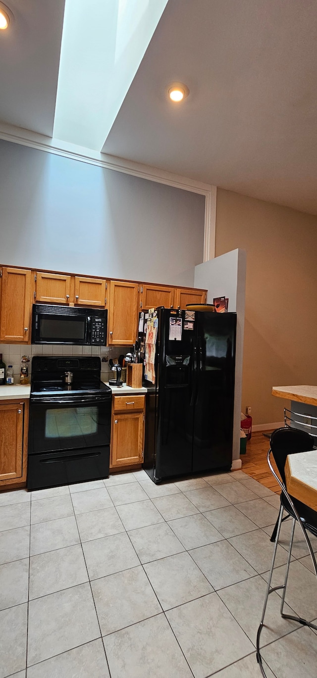 kitchen featuring decorative backsplash, crown molding, light tile patterned floors, and black appliances