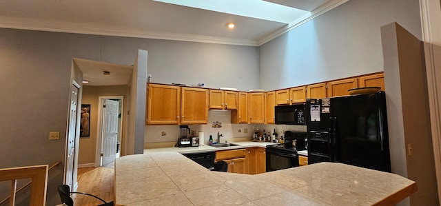 kitchen with kitchen peninsula, ornamental molding, sink, black appliances, and tile counters