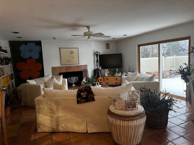 living area with ceiling fan and a tiled fireplace