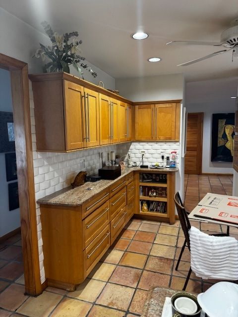 kitchen with light tile patterned floors, ceiling fan, brown cabinets, and backsplash