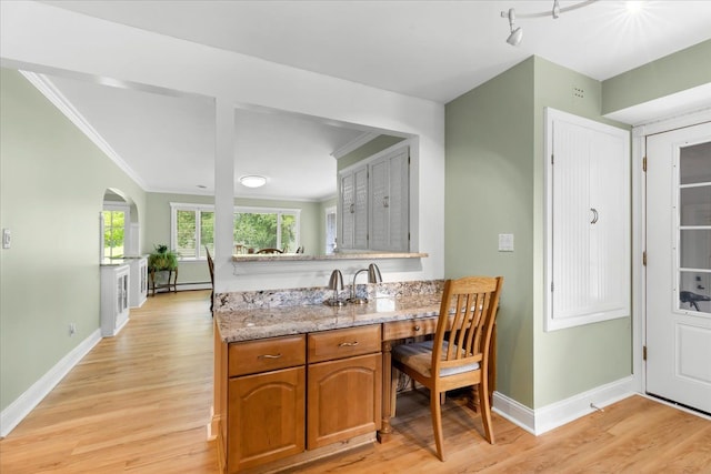 kitchen featuring a baseboard radiator, ornamental molding, light stone countertops, and light hardwood / wood-style flooring