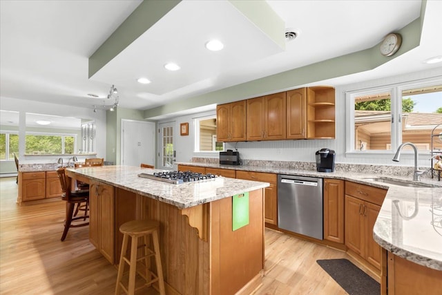 kitchen with appliances with stainless steel finishes, a center island, a wealth of natural light, and sink