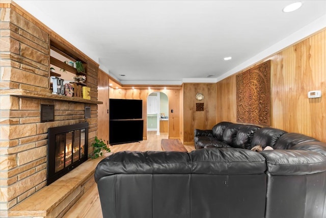 living room with a large fireplace, light hardwood / wood-style flooring, and wood walls