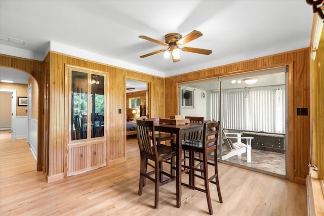 dining area with wooden walls, plenty of natural light, ceiling fan, and light wood-type flooring