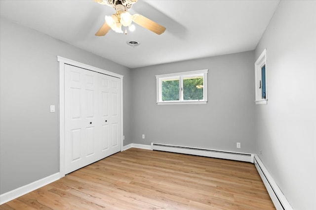 unfurnished bedroom with a closet, ceiling fan, baseboard heating, and light hardwood / wood-style floors