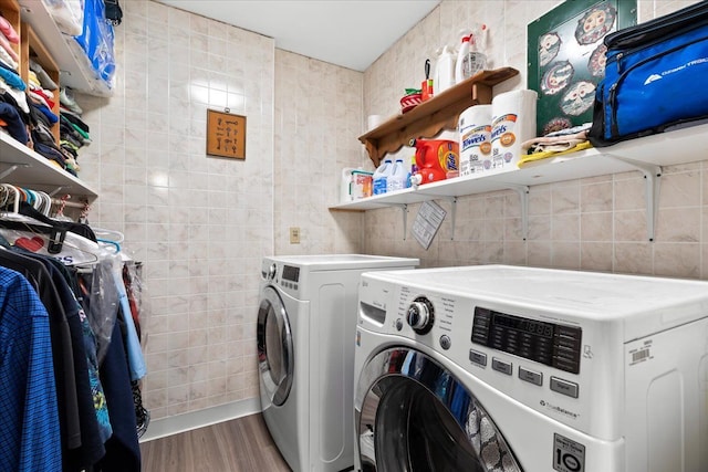 clothes washing area with tile walls, hardwood / wood-style flooring, and separate washer and dryer