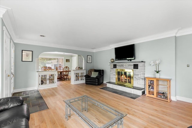 living room featuring a stone fireplace, ornamental molding, and hardwood / wood-style flooring