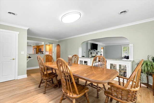 dining room with crown molding and light hardwood / wood-style floors