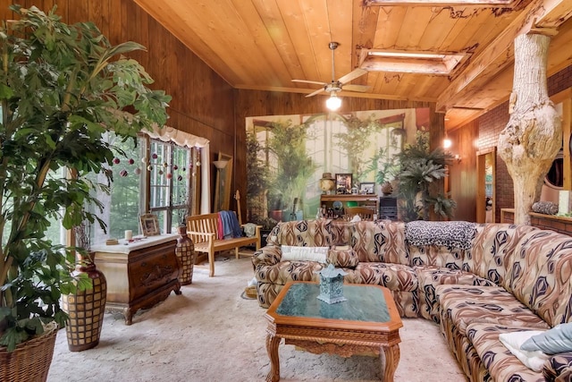 carpeted living room with vaulted ceiling with skylight, ceiling fan, wood ceiling, and wooden walls