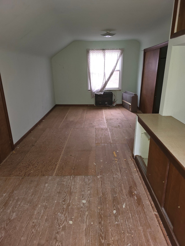 additional living space featuring lofted ceiling and light wood-type flooring