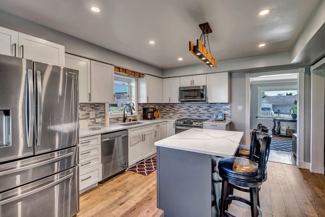 kitchen with sink, a center island, stainless steel appliances, and light wood-type flooring