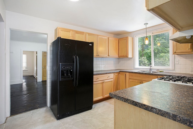 kitchen featuring a sink, dark countertops, light brown cabinets, and black fridge