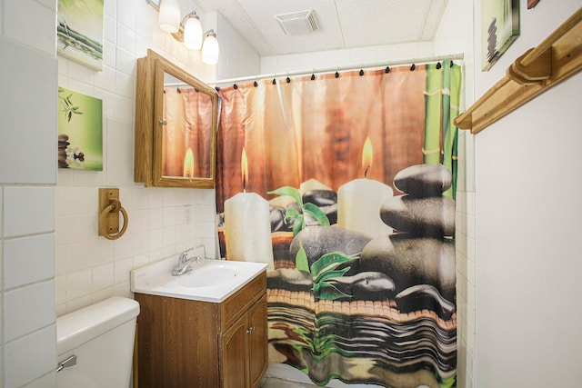 full bath featuring visible vents, toilet, tile walls, decorative backsplash, and vanity