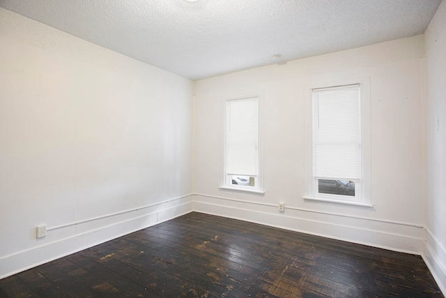 unfurnished room with baseboards, a textured ceiling, and dark wood-style floors