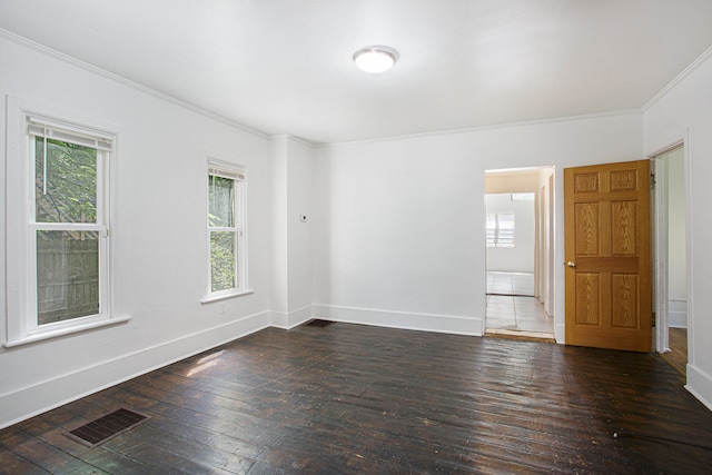 empty room featuring crown molding, baseboards, visible vents, and wood-type flooring