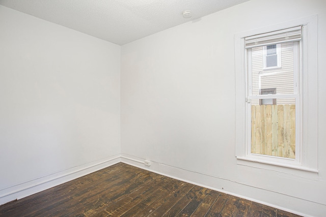 spare room featuring dark wood-type flooring and a textured ceiling