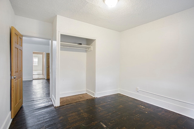 unfurnished bedroom featuring hardwood / wood-style floors, baseboards, a closet, and a textured ceiling