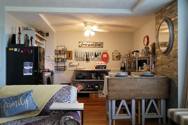 kitchen featuring dark hardwood / wood-style flooring, ceiling fan, black fridge, and a textured ceiling