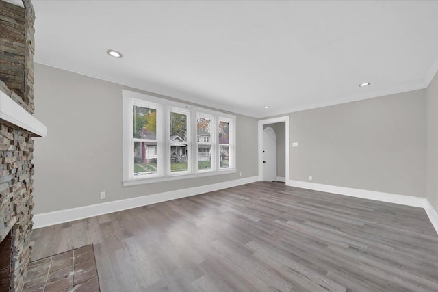 unfurnished living room featuring hardwood / wood-style floors and a stone fireplace