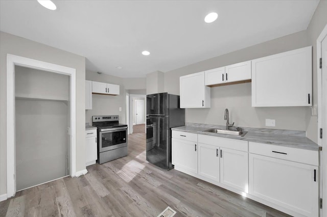 kitchen featuring white cabinetry, black fridge, stainless steel electric range oven, and sink