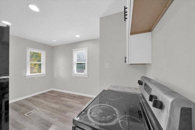 kitchen with electric range, light hardwood / wood-style floors, and white cabinetry