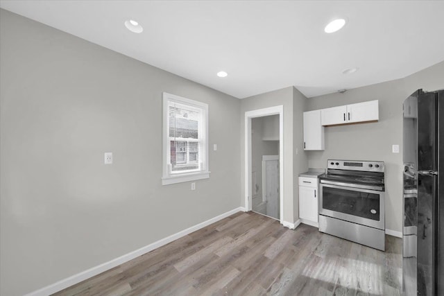 kitchen with black refrigerator, light hardwood / wood-style flooring, white cabinetry, and stainless steel electric stove