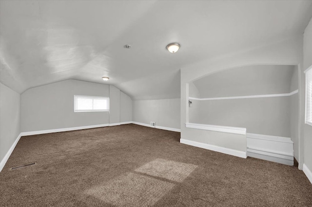 bonus room with dark carpet and vaulted ceiling