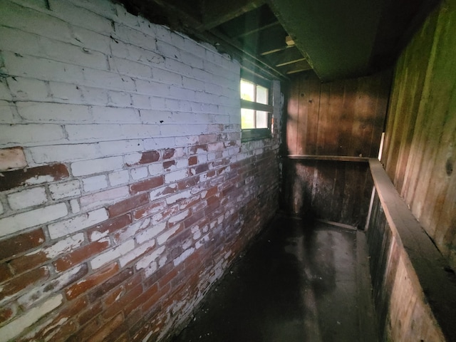 basement featuring wood walls and brick wall