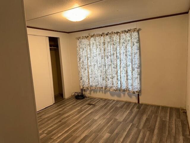 unfurnished bedroom featuring ornamental molding, dark wood-type flooring, and a closet