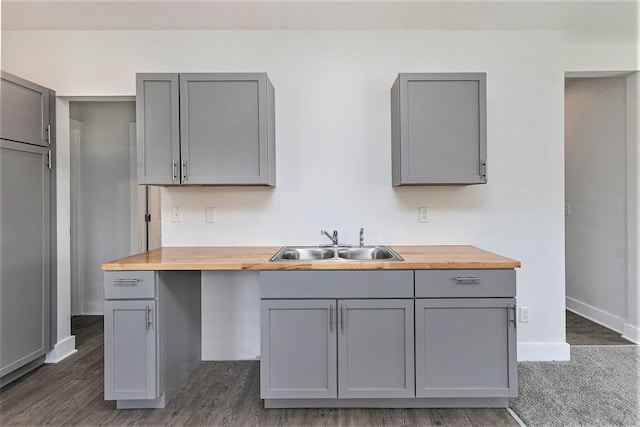 kitchen featuring butcher block countertops, dark hardwood / wood-style flooring, gray cabinetry, and sink