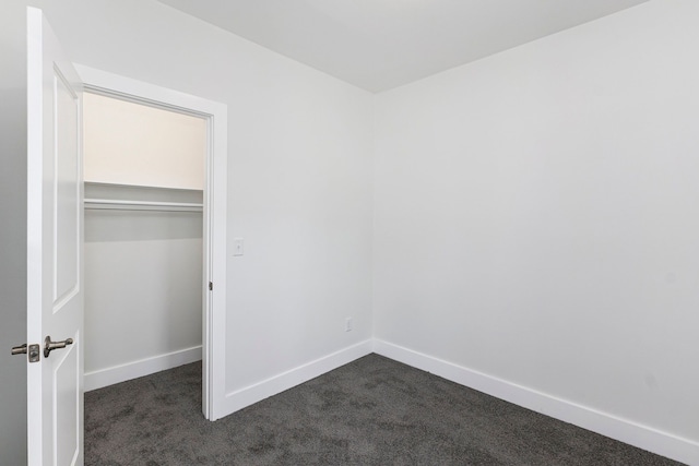 unfurnished bedroom featuring dark colored carpet and a closet