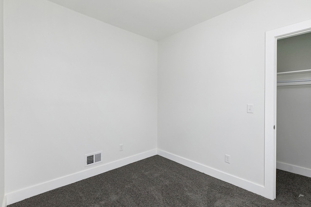 unfurnished bedroom with a closet and dark colored carpet