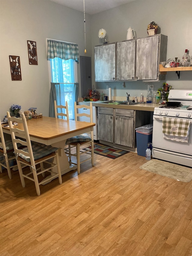 kitchen featuring white gas range, sink, and light wood-type flooring