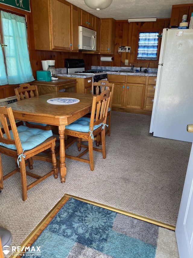 6344 W Houghton Lake Rd, Houghton Lake, MI 48629 - kitchen featuring white appliances, brown cabinetry, light colored carpet, and light countertops