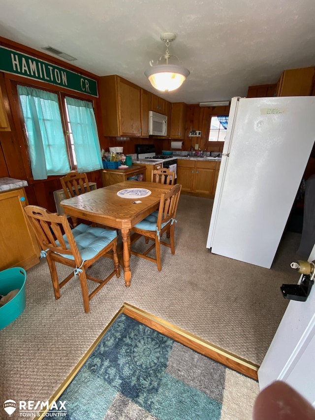 carpeted dining room featuring wooden walls