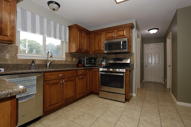 807 War Bonnet Dr, Tecumseh, MI 49286 - kitchen featuring light tile patterned flooring, brown cabinets, backsplash, and stainless steel appliances