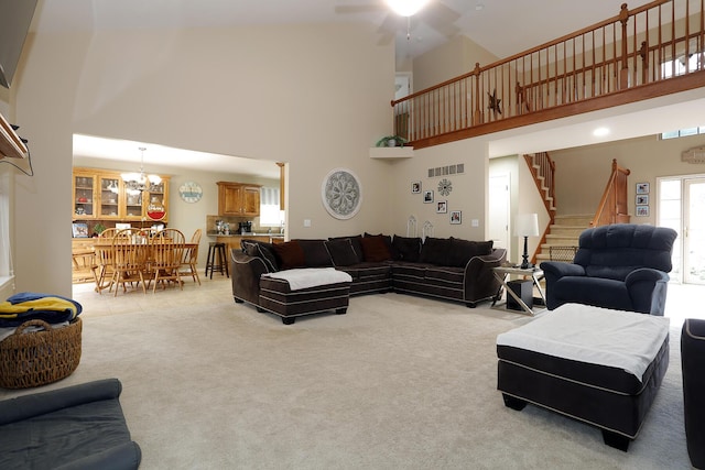 807 War Bonnet Dr, Tecumseh, MI 49286 - living area featuring visible vents, stairway, light carpet, ceiling fan with notable chandelier, and a high ceiling
