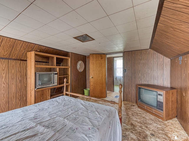 unfurnished bedroom with carpet, wood walls, and lofted ceiling