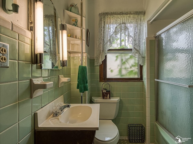 full bathroom with toilet, vanity, tile walls, and combined bath / shower with glass door