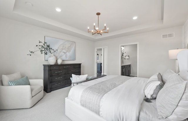 carpeted bedroom with connected bathroom, a chandelier, and a tray ceiling