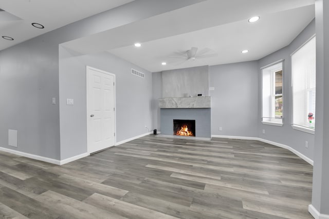 unfurnished living room featuring light wood-type flooring, a brick fireplace, and ceiling fan