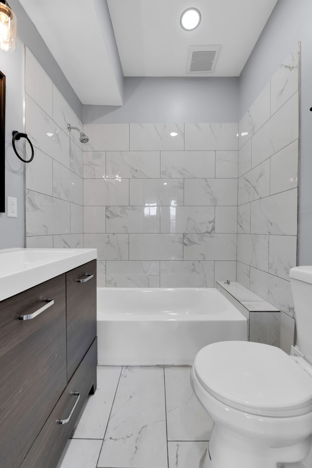 full bathroom featuring tiled shower / bath, vanity, tile walls, and toilet