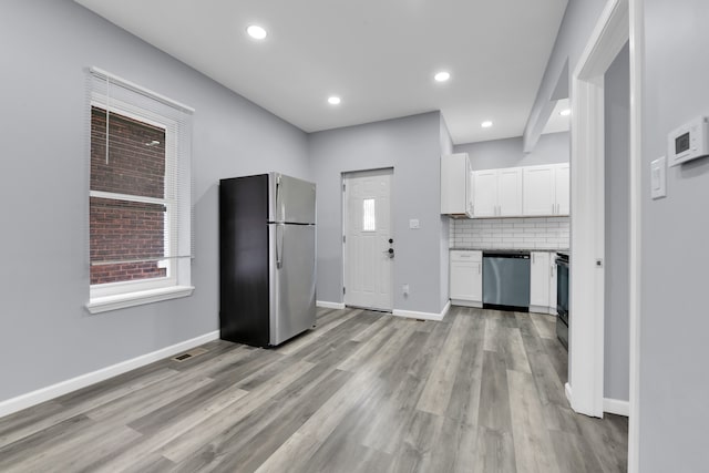 kitchen with white cabinets, backsplash, stainless steel appliances, and light hardwood / wood-style flooring