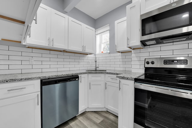 kitchen with white cabinetry, sink, stainless steel appliances, tasteful backsplash, and light hardwood / wood-style flooring