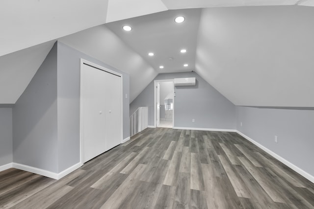 bonus room featuring a wall mounted air conditioner, hardwood / wood-style floors, and vaulted ceiling