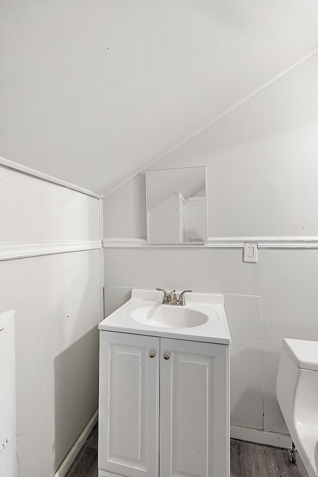 bathroom featuring toilet, hardwood / wood-style floors, vanity, and vaulted ceiling