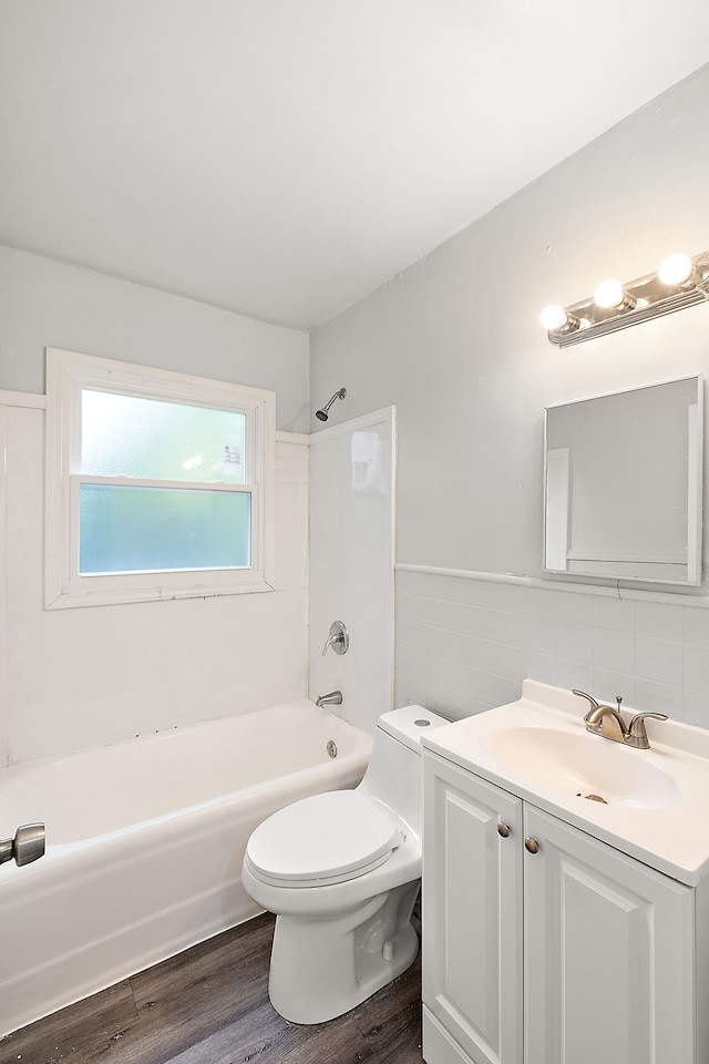 full bathroom with tile walls, wood-type flooring, toilet, vanity, and bathtub / shower combination