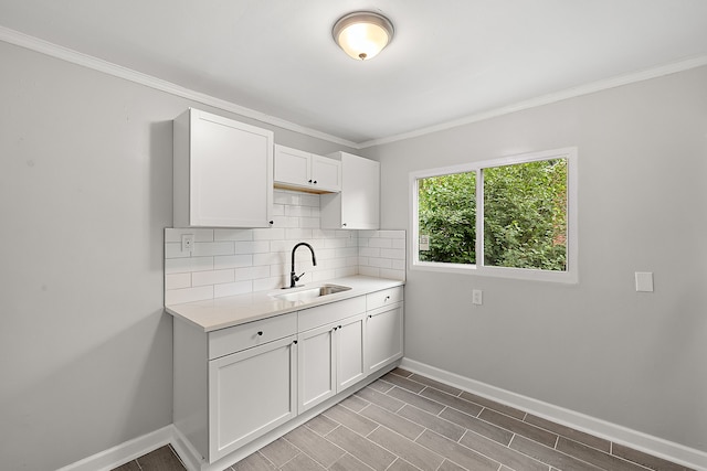 kitchen featuring crown molding, sink, tasteful backsplash, light hardwood / wood-style floors, and white cabinetry