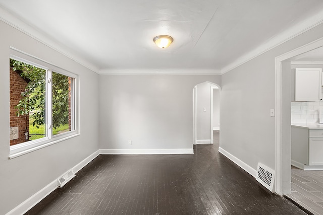 empty room featuring crown molding and dark wood-type flooring