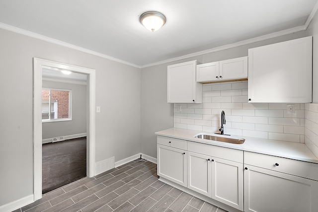 kitchen with hardwood / wood-style floors, sink, ornamental molding, tasteful backsplash, and white cabinetry